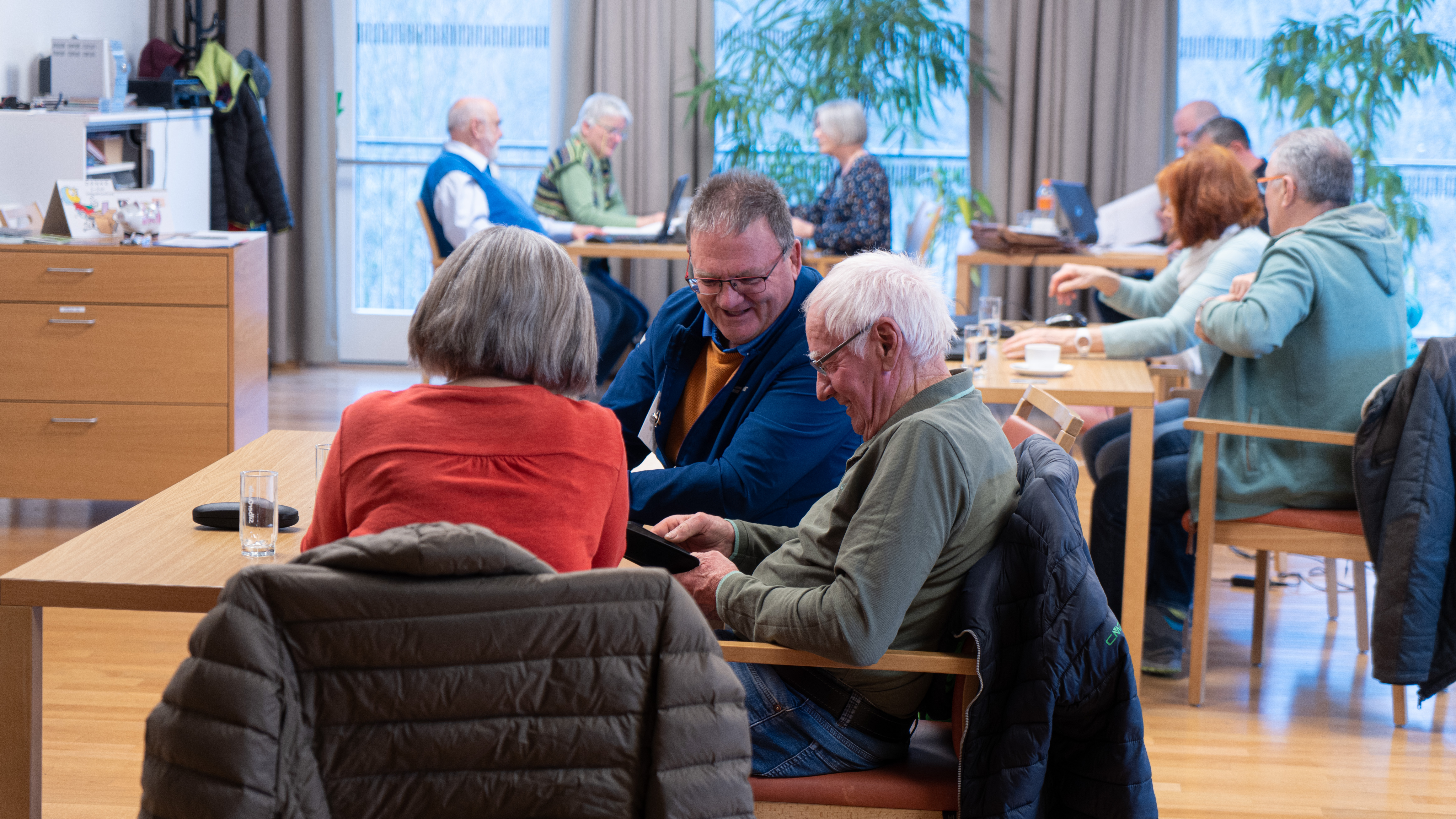 Foto von älteren Menschen die digitale Geräte nutzen.